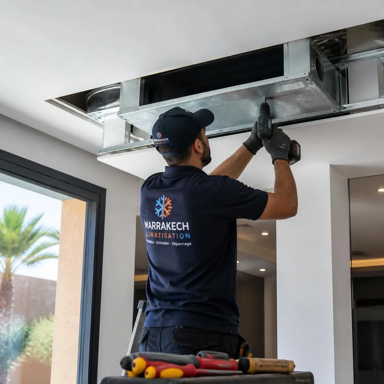 Technicien d'une société de climatisation à Marrakech effectuant l'installation d'un système gainable.